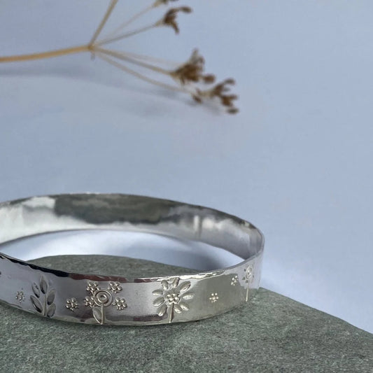 Wide band bangle with flower stampings