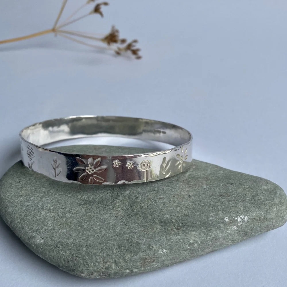 Wide band bangle with flower stampings