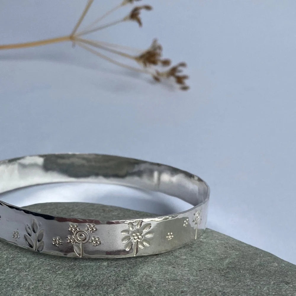 Wide band bangle with flower stampings