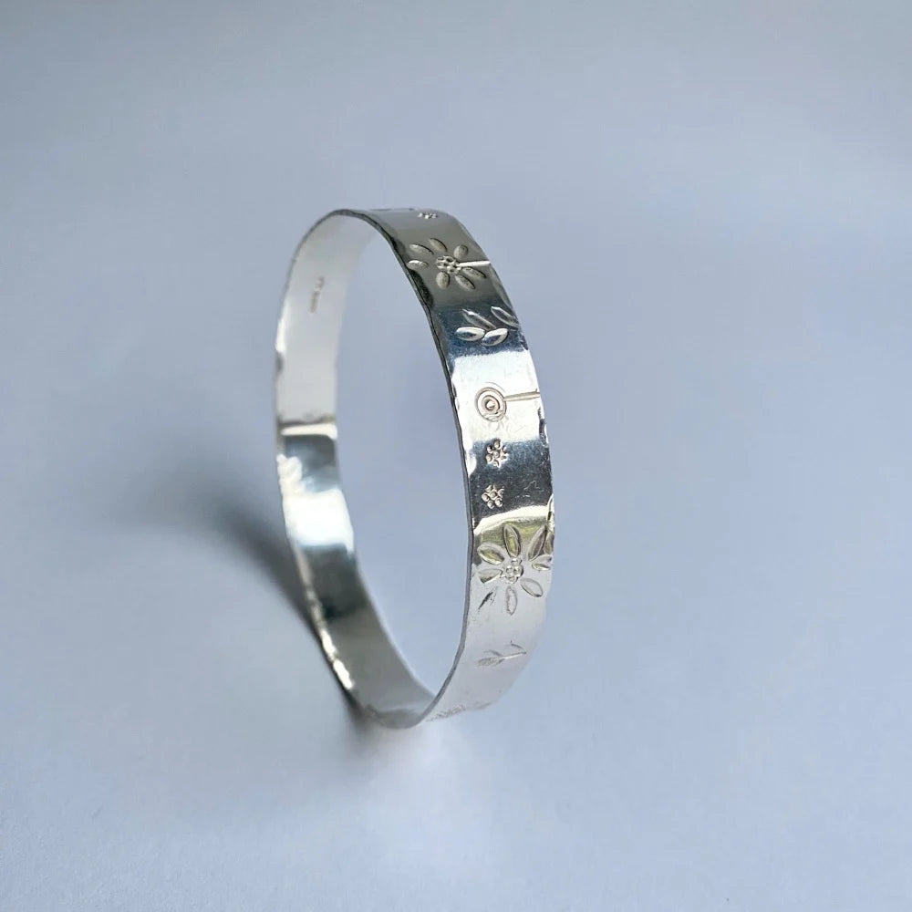 Wide band bangle with flower stampings